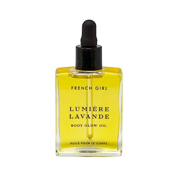 A clear glass bottle of FRENCH GIRL Organic Hydrating Lavender Body Glow Oil (2 oz) with a black dropper cap and yellow organic oils, featuring the product name and details in sleek black text on the label.