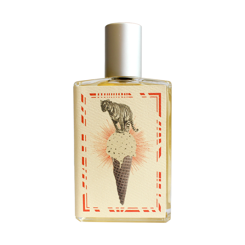 Introducing the Imaginary Authors A Whiff of Wafflecone - Large Size perfume, adorned with a silver cap. The label boasts an illustration of a tiger majestically perched atop an ice cream cone with a waffle pattern. The cone holds a delightful scoop of vanilla ice cream sprinkled with chocolate bits. This vintage-style design is framed by red decorative borders, evoking a nostalgic sense of sweet memories.