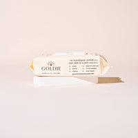 A package of Goldie - So Fresh, So Clean Probiotic Wipes for dogs rests on a white rectangular block with a beige background. The packaging features plant-based, hypoallergenic, soothing, hydrating, and biodegradable benefits.