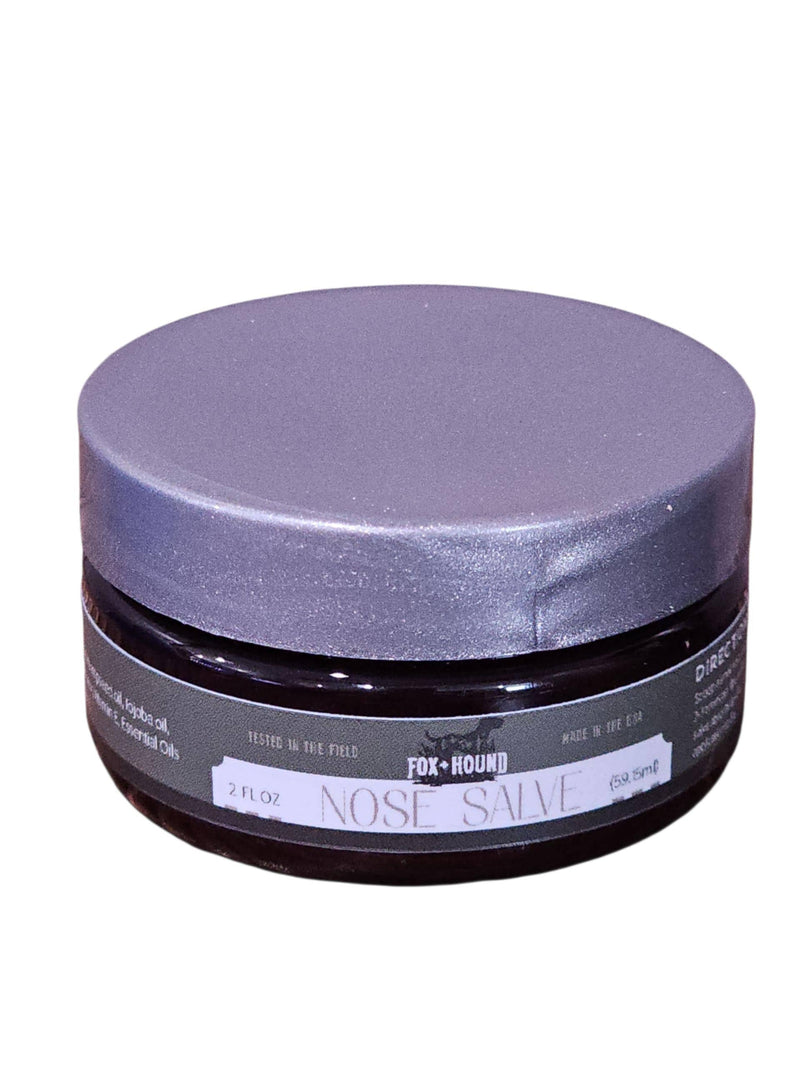 A round, dark jar with a silver lid labeled "Fox + Hound Nose Salve For Dogs, Butter, Balm." This natural balm by Fox + Hound moisturizes and soothes dry dog noses with gentle ingredients. 2 fl oz size.