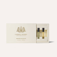 A cream-colored Caswell-Massey Fragrance Discovery Collection box with gold lettering is partially open, revealing two small glass eau de parfum vials inside.