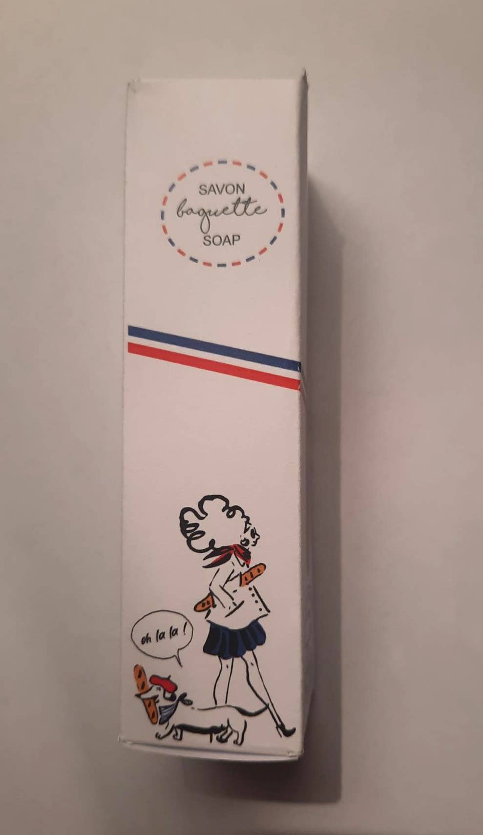 A box of Senteurs De France "Baguette" Soap features a cartoon woman with a baguette and dog saying "oh la la," plus a French flag stripe—a charming Parisian-themed keepsake by Senteurs De France.