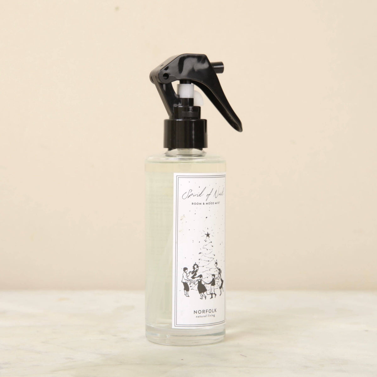 A clear spray bottle with a black trigger nozzle sits on a light surface. The label reads "Norfolk Natural Living Spirit of Noel Christmas Room Mist," ideal for adding festive fragrance and a cozy ambiance to any space.