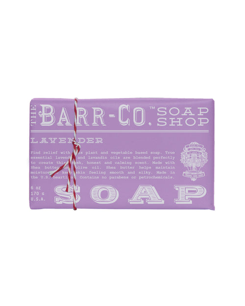 Introducing the Barr-Co. Lavender Triple Milled Bar Soap by Barr-Co. This soap features a soothing lavender scent enriched with olive oil, known for its natural ingredients and benefits. It comes packaged in a purple box with white text, elegantly wrapped with a red and white string for an extra touch of charm.