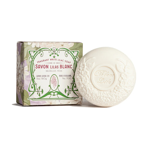 The round, embossed white soap from Kala is beautifully presented in a floral-patterned cardboard box. The packaging displays the text "Blanc Lila Lilac Bath Soap," which reflects its delightful French lilac scent, highlighting that it is a fragrant white lilac soap.