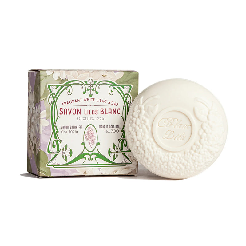 The round, embossed white soap from Kala is beautifully presented in a floral-patterned cardboard box. The packaging displays the text "Blanc Lila Lilac Bath Soap," which reflects its delightful French lilac scent, highlighting that it is a fragrant white lilac soap.