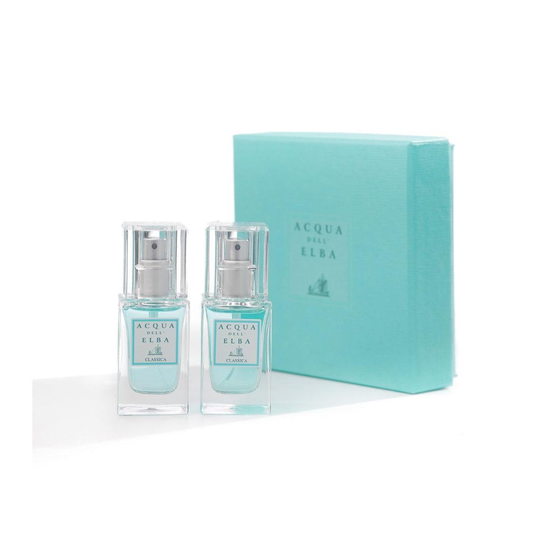 Two small bottles of Acqua dell’Elba Classica Uomo Duo by Acqua dell’Elba, featuring light blue liquid, are displayed next to a matching light blue gift box against a white background.