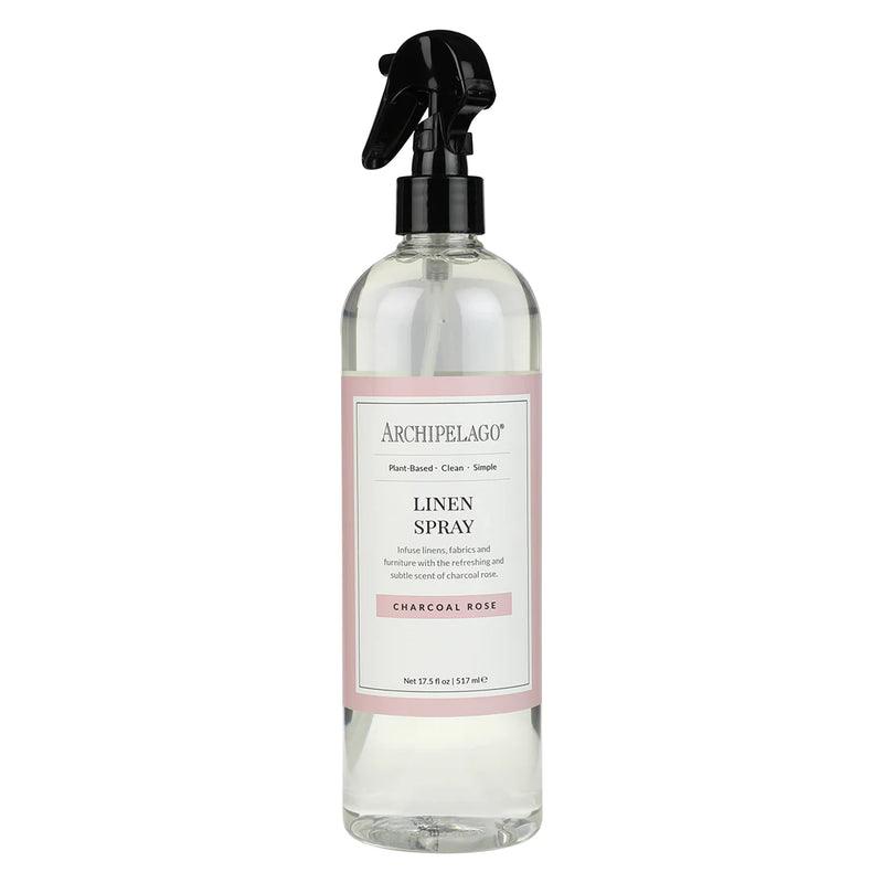 A transparent spray bottle labeled "Archipelago Charcoal Rose Linen Spray" with a black spray nozzle, displaying a clear liquid inside.