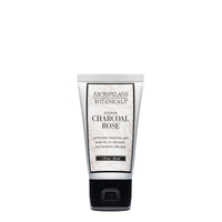 Archipelago Botanicals' Charcoal Rose Travel Size Lotion features activated charcoal and rose oil to exfoliate and hydrate skin. This vegan formula comes in a white tube with black and gold text, displayed upright on a white background.