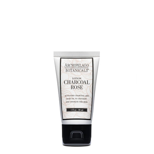 Archipelago Botanicals' Charcoal Rose Travel Size Lotion features activated charcoal and rose oil to exfoliate and hydrate skin. This vegan formula comes in a white tube with black and gold text, displayed upright on a white background.