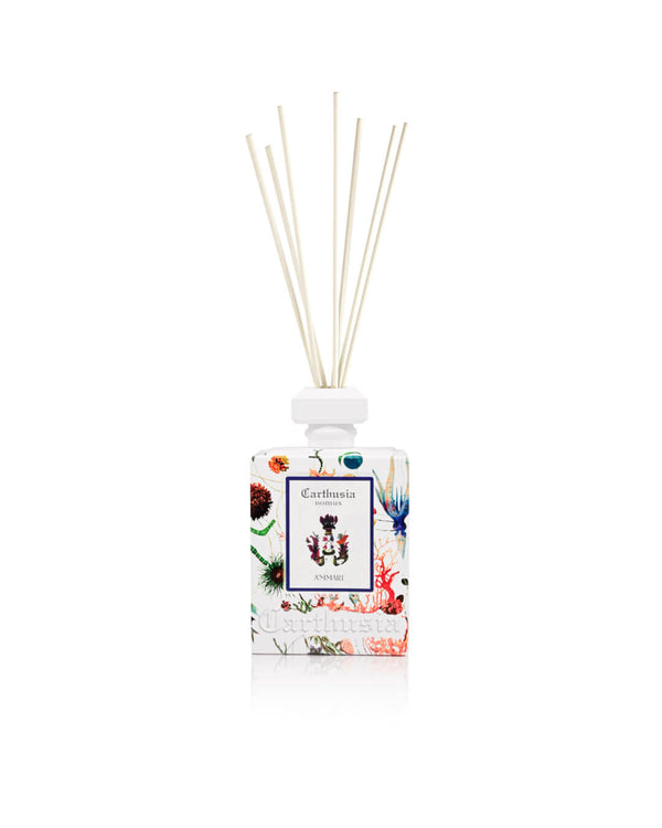The Carthusia I Profumi di Capri A'mmare Reed Diffuser (480ml) features a clear bottle with floral designs, a white cap, and multiple reed sticks for a sophisticated ambiance. The "Anima" label displays colorful botanical illustrations.