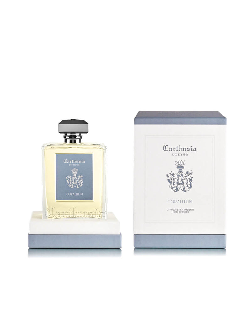 A 230ml Carthusia Corallium Reed Diffuser by Carthusia I Profumi di Capri features a glass bottle with silver cap beside its white and blue box, both with the brand’s crest, reflecting its woody aromatic home fragrance.