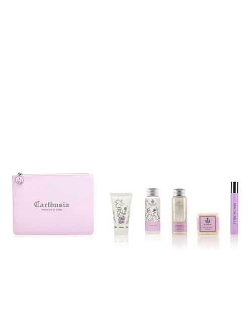 A collection of personal care items displayed against a white background. The set includes a purple zippered pouch labeled "Carthusia I Profumi de Capri Carthusia Fiori di Capri Travel Clutch Bag," four small bottles of lotions and creams in various sizes and designs, all featuring the Flowers of Capri scent, and a small rectangular bar of soap.