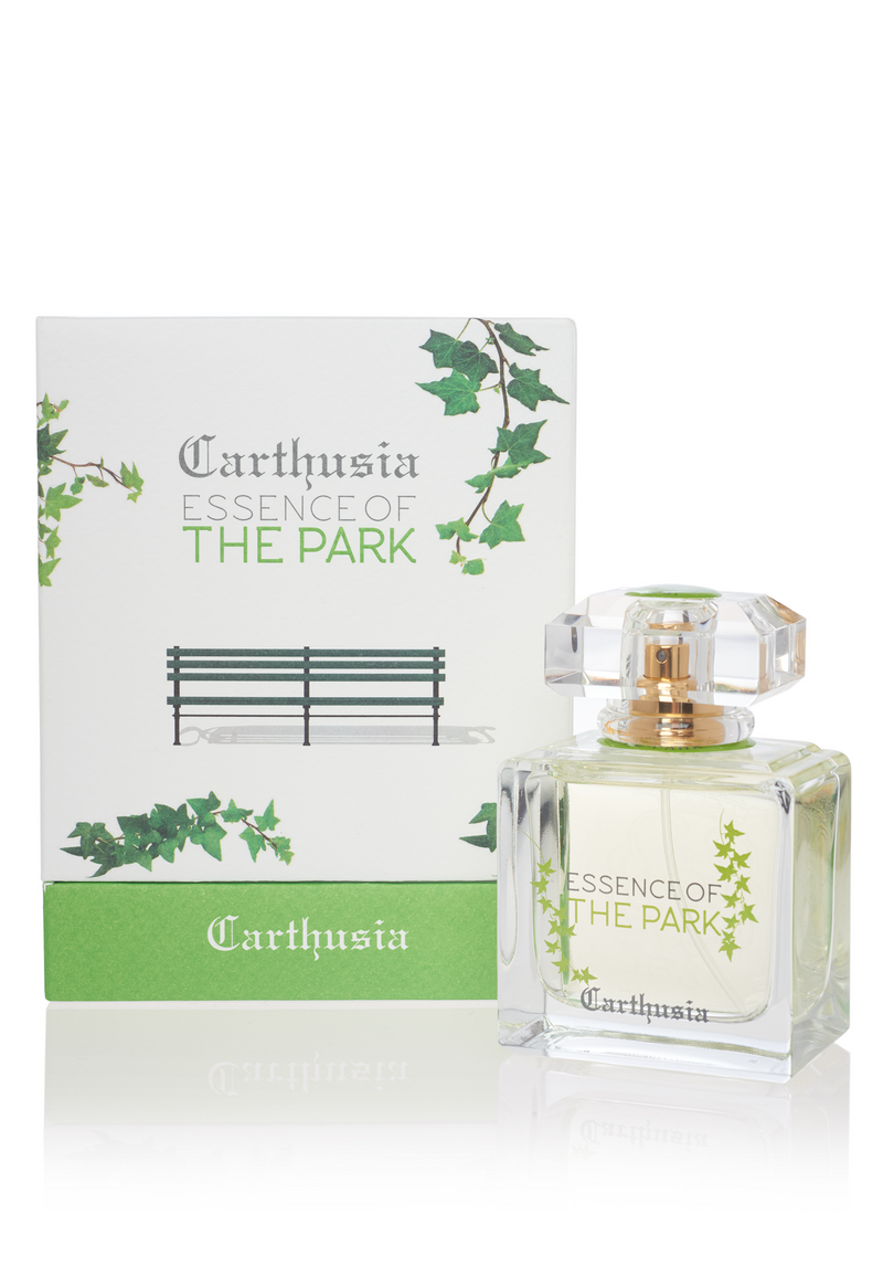 A bottle of Carthusia I Profumi de Capri "Essence of the Park" parfum next to its box, which is decorated with green ivy and an image of a park bench. The perfume has a
