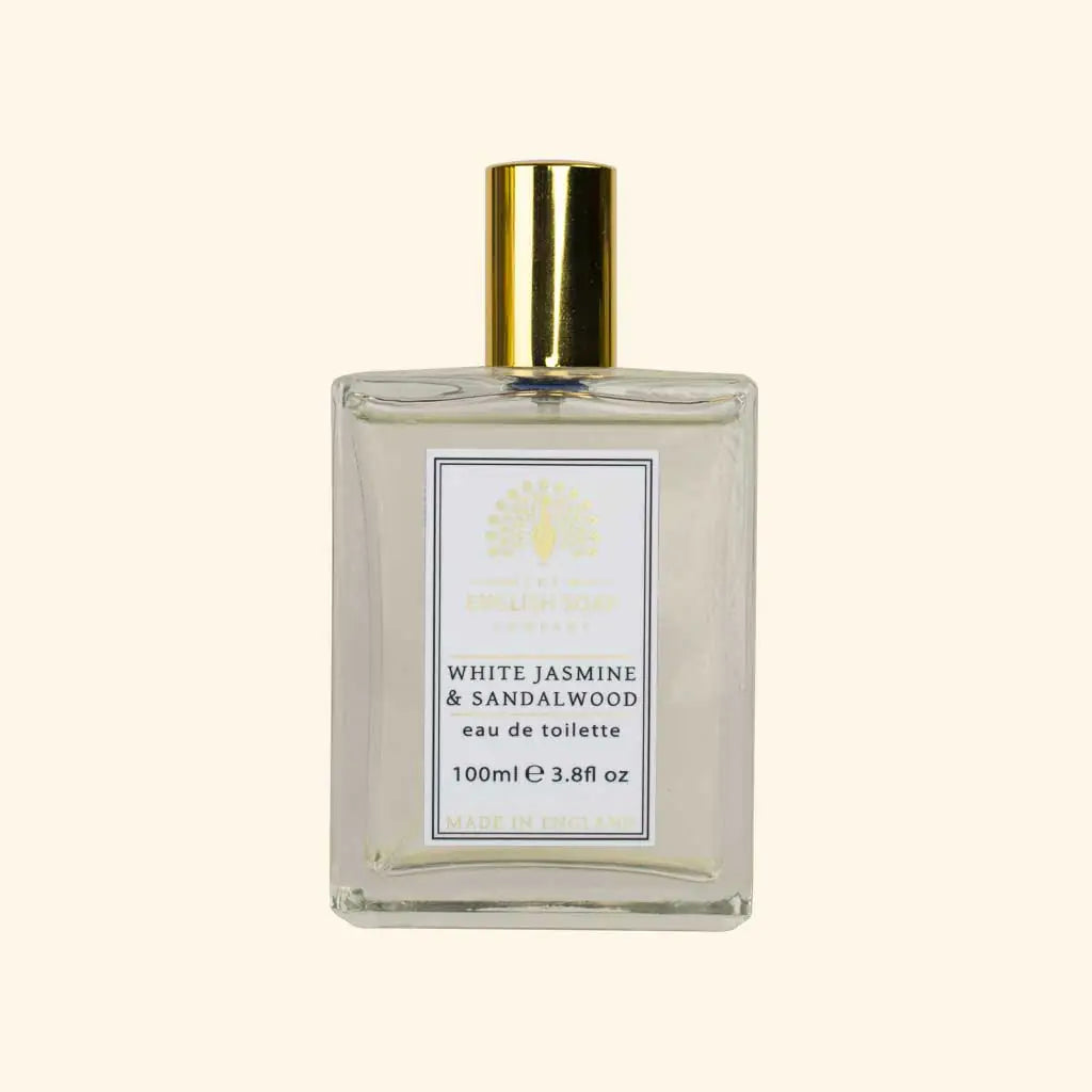 The English Soap Co. White Jasmine Eau de Toilette comes in a clear glass bottle with a gold cap and decorative logo, labeled "White Jasmine & Sandalwood eau de toilette, 100ml," a vegan fragrance made in England.