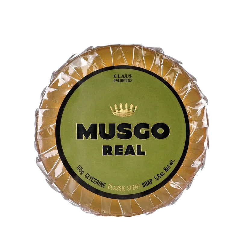A round bar of Claus Porto 1887 Musgo Real Classic Scent Glycerin Pre-Shave Soap, wrapped in golden foil with a green and gold label, displaying the brand and product name prominently.