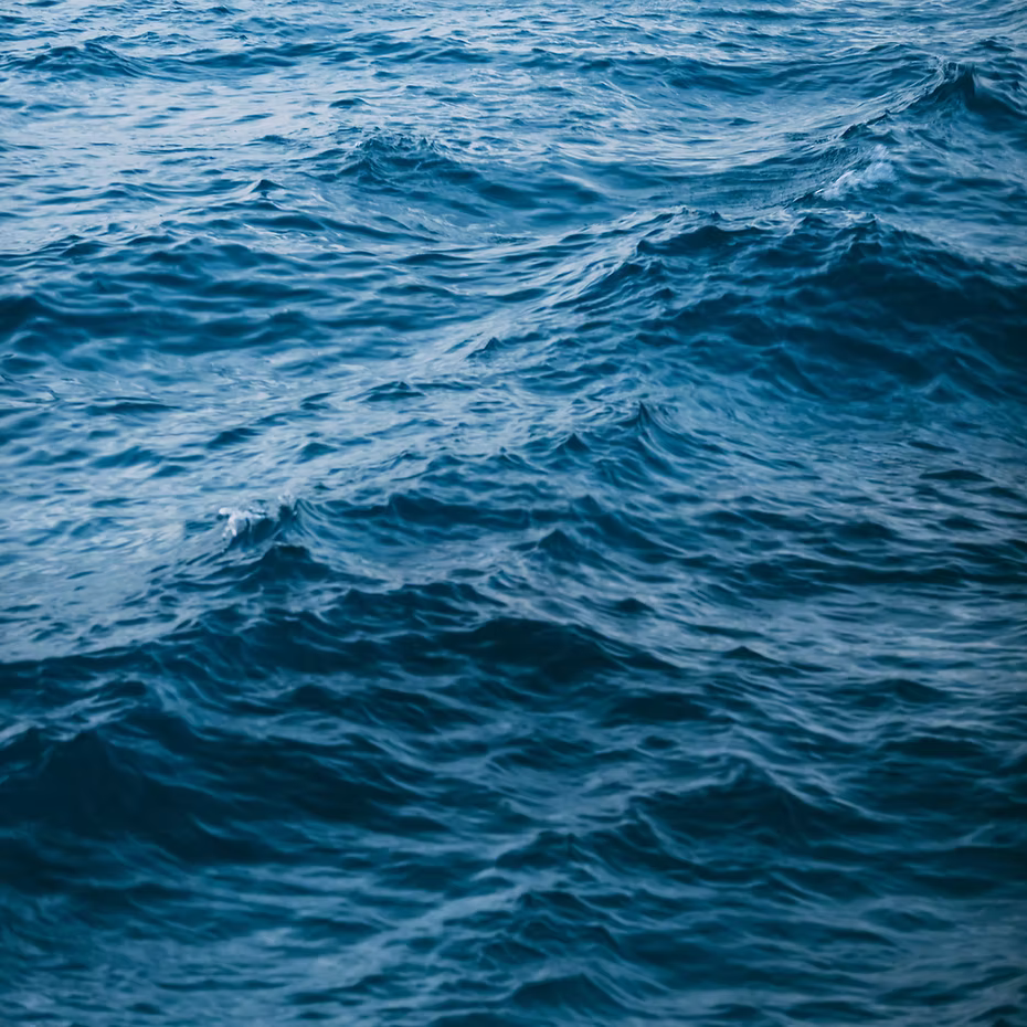 The deep blue waves with gentle ripples and white highlights evoke the soothing sensation of ISULA Storia di Mare - Sea Story Shampoo by ISULA parfums, infusing the scene with calming oceanic aromatics under natural light.