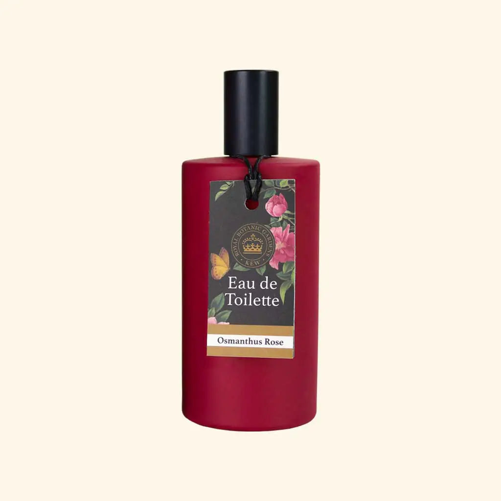 A red bottle of The English Soap Co. Kew Gardens Osmanthus Rose Eau de Toilette with a black cap and a beige floral label featuring butterflies, highlighting the vegan perfume’s delicate scent.