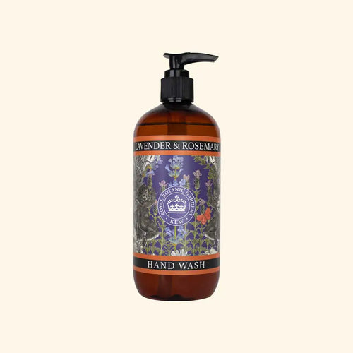 A brown pump bottle labeled "The English Soap Co. Kew Gardens Lavender and Rosemary Hand Wash," adorned with intricate botanical illustrations of lavender, rosemary, and other plants. The formulation is enriched with aloe vera and vitamin E. The label proudly features a seal reading "Botanic Gardens Kew." The background is a plain, light beige color.