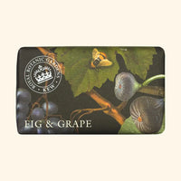 The English Soap Co. Kew Gardens Fig and Grape Soap, a vegan shea butter bar, is wrapped in paper with figs, grapes, leaves, and a bee. The label features “Royal Botanic Gardens Kew” and “Fig & Grape,” set on a soft beige background.