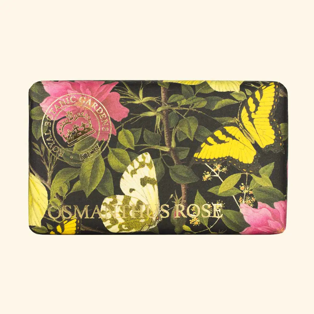 A rectangular bar of The English Soap Co. Kew Gardens Osmanthus Rose Soap wrapped in floral paper with pink roses, green leaves, yellow butterflies, gold "OSMANTHUS ROSE" text, and a circular seal on the top left.