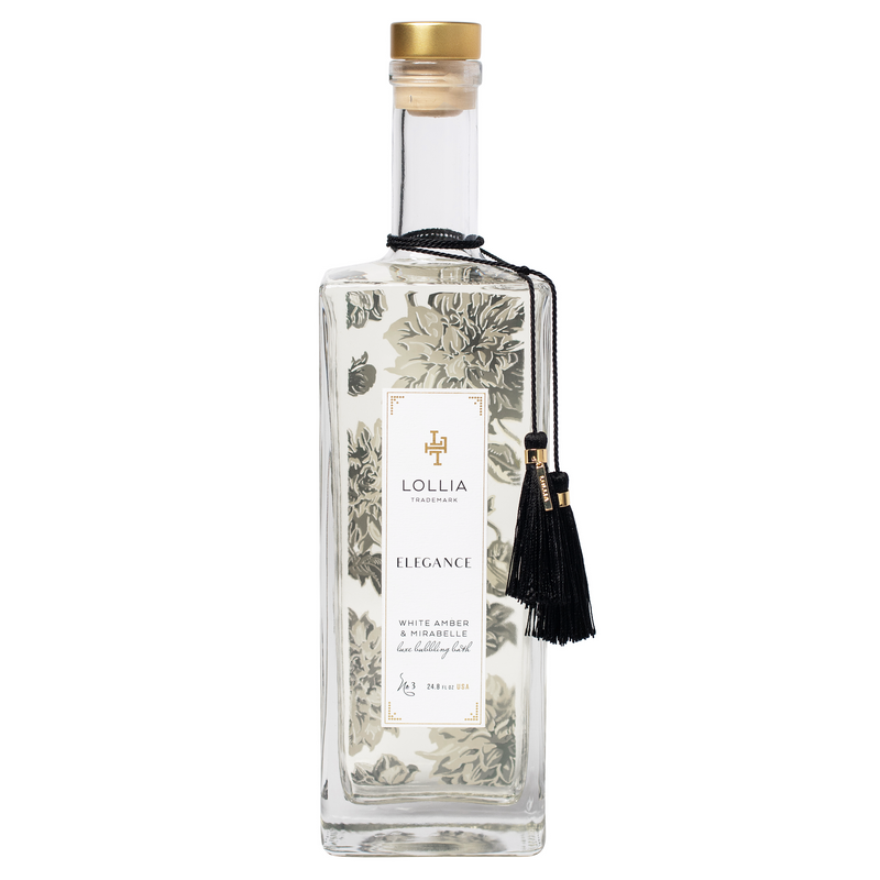 A tall, elegant glass bottle of Margot Elena Lollia Elegance Bubble Bath, featuring a clear liquid with hints of white amber, ornate botanical print, and a black tassel on the neck.