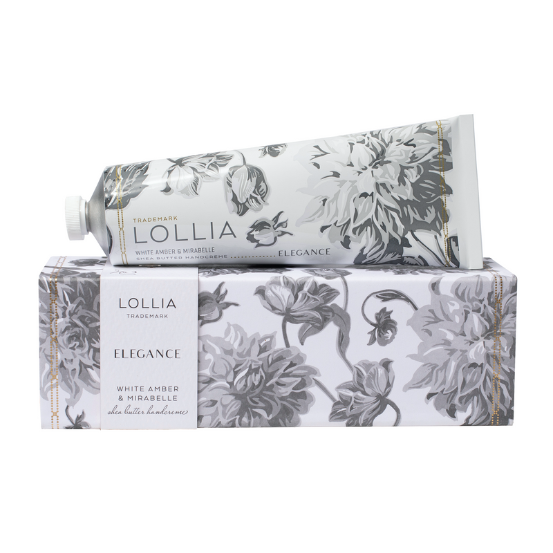 Elegant packaging of Margot Elena's Lollia Elegance Shea Butter Handcreme featuring white and silver floral designs on the boxes and tubes of White Amber & Mirabelle and mineral bath products.