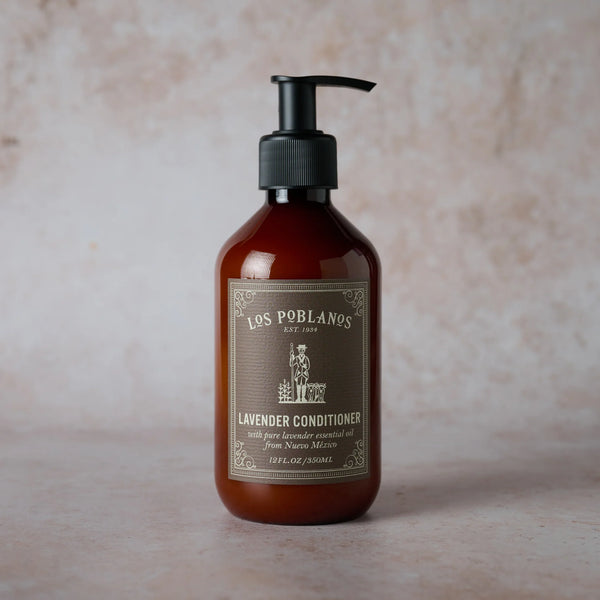 A brown pump bottle of Los Poblanos Lavender Hair Conditioner rests on a light textured surface, featuring an ornate label and soothing lavender essential oil for gentle, all-natural hair care.
