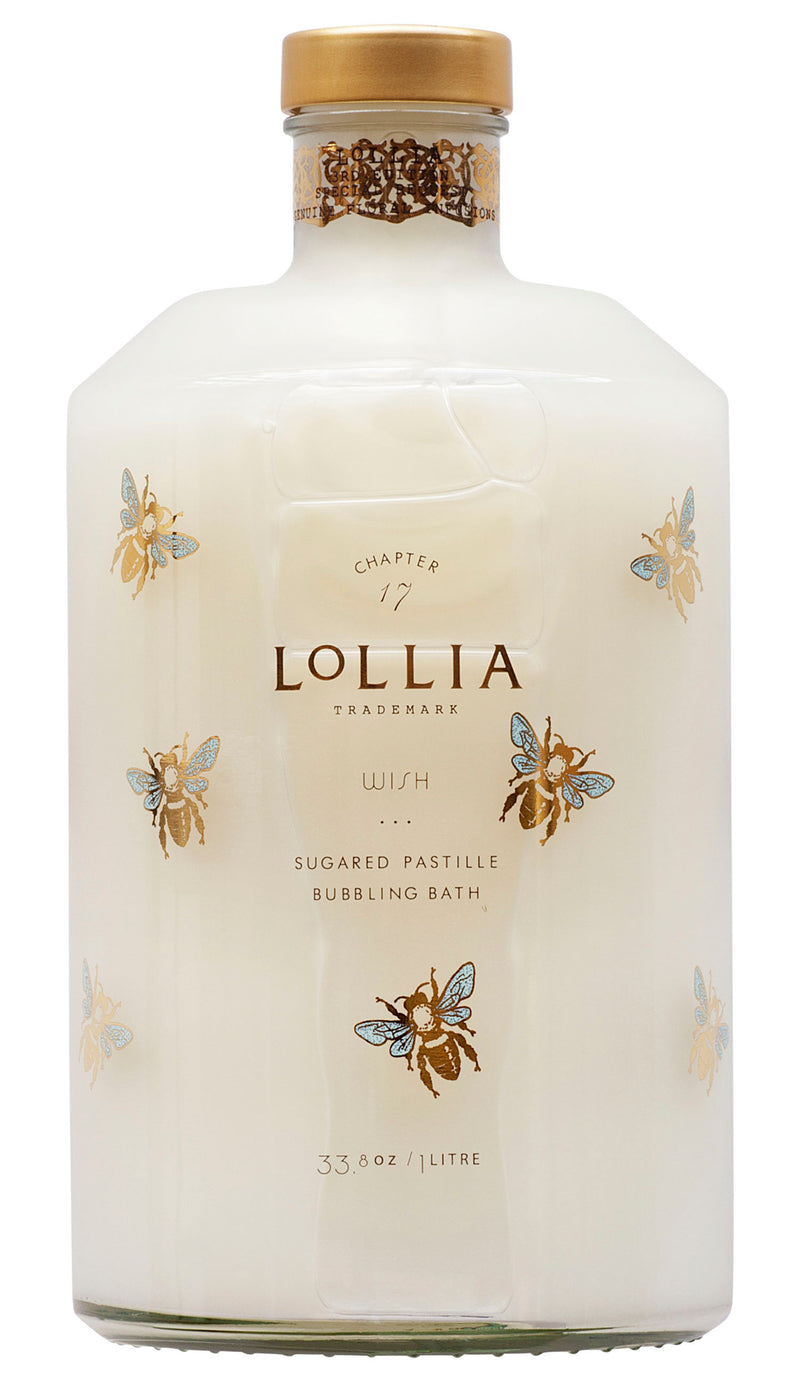 A clear bottle of Margot Elena Lollia Wish Bubble Bath with gold and blue bee illustrations, filled with milky-white liquid rich in Olive Fruit Oil, and topped with a gold cap.