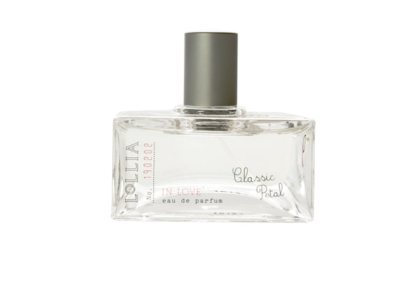 A clear rectangular bottle with a silver cap, labeled "Lollia in Love" by Margot Elena, holds Eau de Parfum featuring sheer romantic floral notes and the essence of Living Rose.