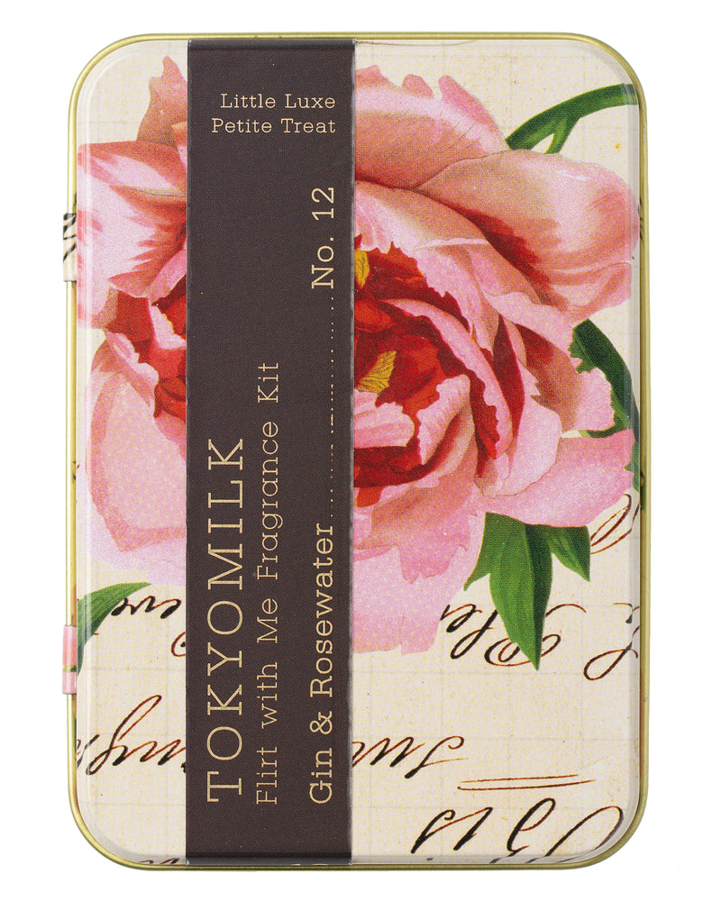 Decorative tin with vintage floral design, labeled "Margot Elena TokyoMilk Gin & Rosewater Flirt With Me Fragrance Kit" in a bold serif typeface on a dark brown ribbon, the background