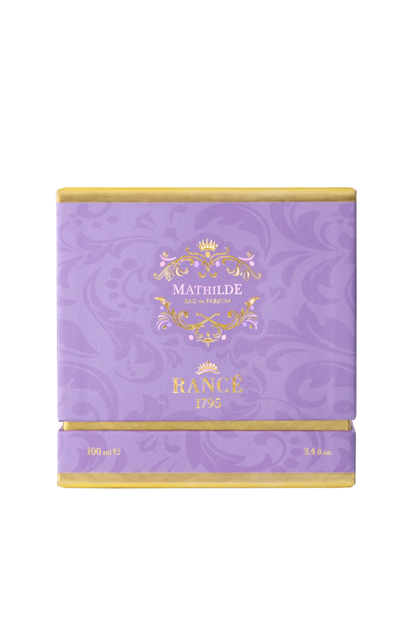 A square, purple luxury box with gold accents displays "Rancé Mathilde Eau de Parfum - 100ml" on the front. The subtle floral pattern hints at its floral woody scent, reflecting the elegance of the Rancé brand.
