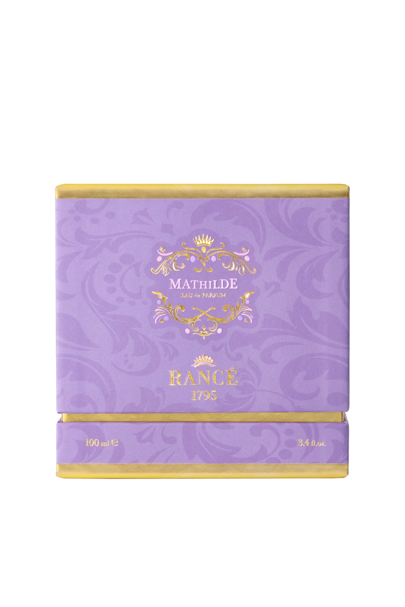 A square, purple luxury box with gold accents displays "Rancé Mathilde Eau de Parfum - 100ml" on the front. The subtle floral pattern hints at its floral woody scent, reflecting the elegance of the Rancé brand.