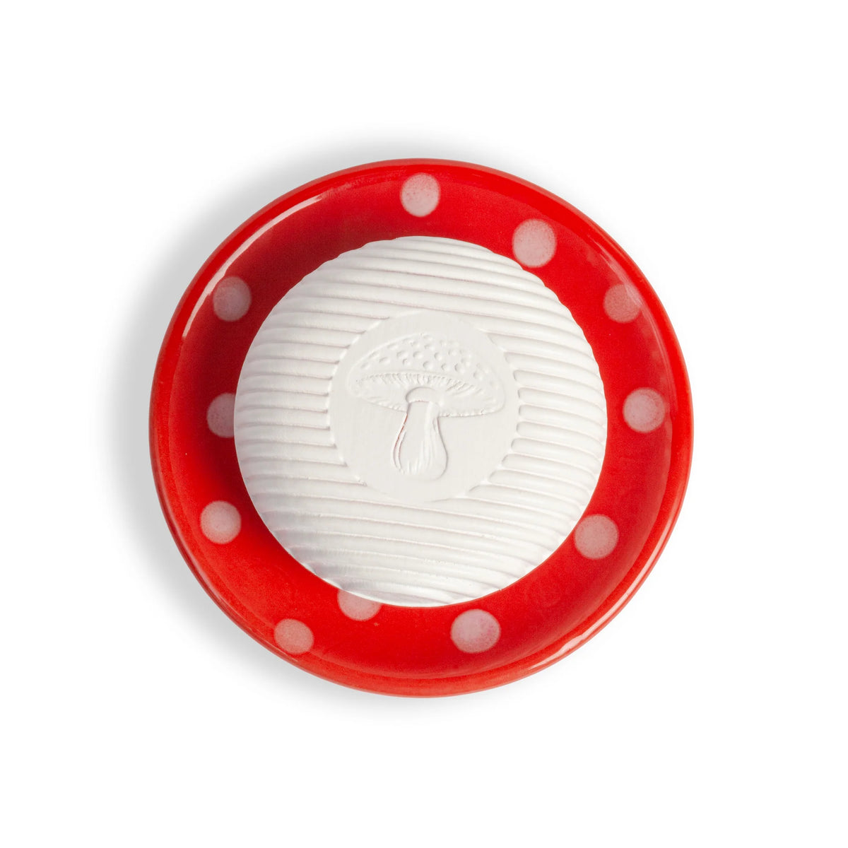 A round white soap with a mushroom design rests on the Kala Swedish Dream Red Mushroom Ceramic Soap Dish, featuring a red base with white polka dots, viewed from above on a white background.