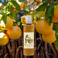 La Bouquetiere Pamplemousse (Grapefruit) Vanille Body Lotion with a pump dispenser is displayed before a tree of ripe yellow grapefruits, capturing the fresh, youthful essence of the fragrance.