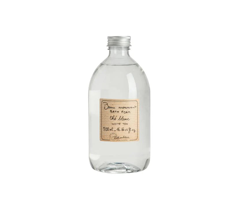A clear glass bottle with a silver screw cap holds Lothantique White Tea Foam Bath, 500 ml. The handwritten label highlights this paraben-free bath foam from Lothantique, shown elegantly against a white background.