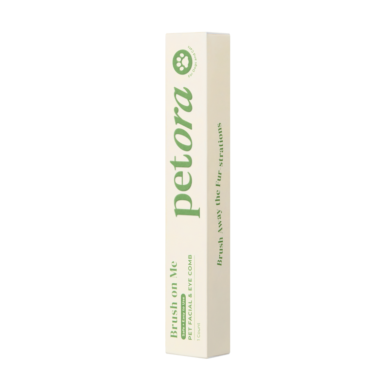 A rectangular cream box stands upright, featuring "Petora" in bold green text. The packaging promotes the Petora BRUSH ON ME Pet Facial & Eye Comb with phrases like "Brush on Me" and "Brush away the fur-strations.