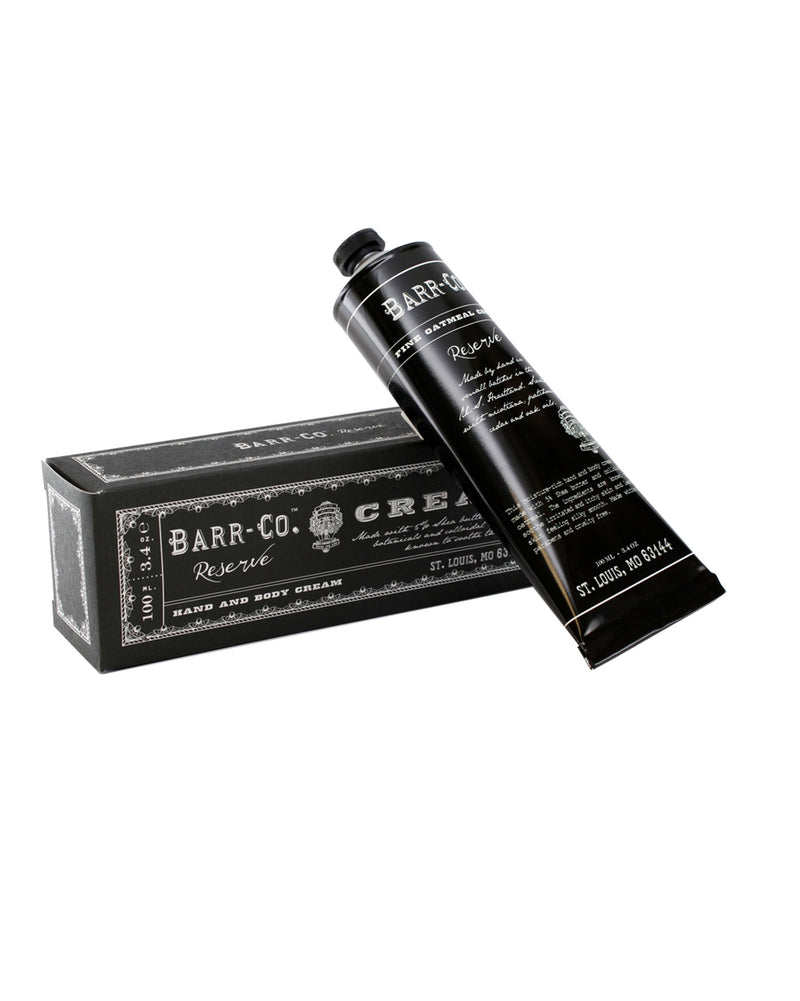 A tube of Barr-Co. Reserve Hand & Body Cream next to its packaging box. The tube and box are black with white text detailing the Barr-Co. brand and product information.