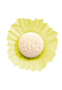 A round, yellow cheese wheel branded with "Roger & Gallet" and infused with osmanthus on its rind, isolated against a black background.