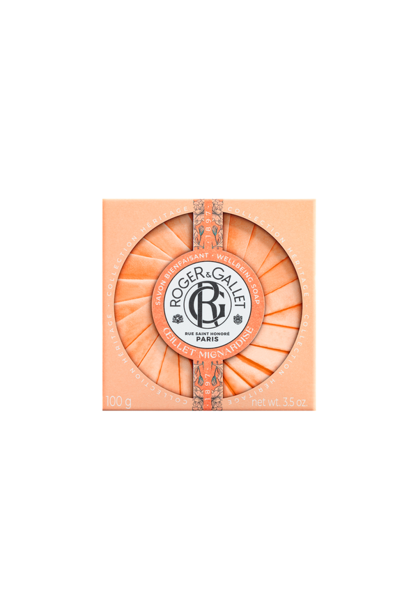 A circular Roger & Gallet Carnation soap bar in an orange-coral hue, featuring intricate embossed designs and a floral fragrance, with the brand logo centered within a regal frame, against a matching background.
