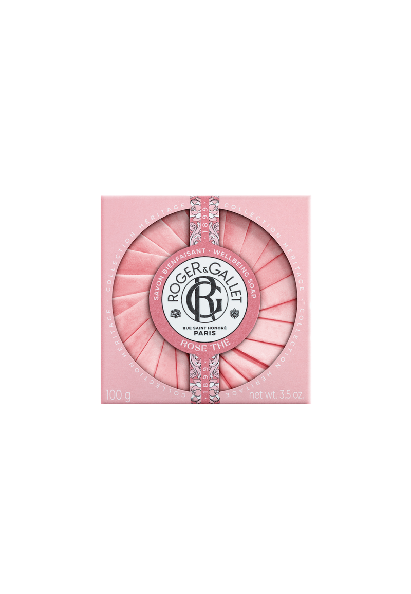 A round Roger & Gallet Tea Rose-scented soap, displayed in a pink case with a textured top resembling rose petals, decorated with a silver band and the company's logo.