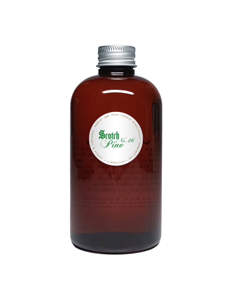 A dark amber bottle with a metallic cap and a green and white label reading "Simpatico Scotch Pine" on a plain background, suggesting the bottle may contain high quality essential oil with a woodsy fragrance.