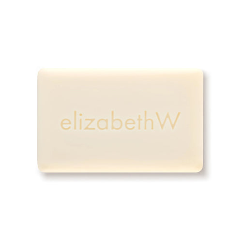 The elizabeth W Botanist's Scent Lab Leaves Bar Soap is a rectangular, off-white bar embossed with "elizabethW," inspired by the Botanist's Scent Lab, capturing natural freshness against a plain white background.