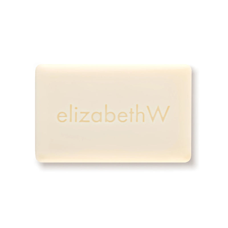 The elizabeth W Botanist's Scent Lab Leaves Bar Soap is a rectangular, off-white bar embossed with "elizabethW," inspired by the Botanist's Scent Lab, capturing natural freshness against a plain white background.