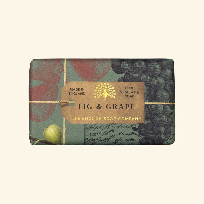 A rectangular bar of vegan-friendly soap in decorative wrapping labeled "The English Soap Co. Anniversary Fig and Grape Soap" by The English Soap Company, featuring images of figs and grapes with a vintage design.