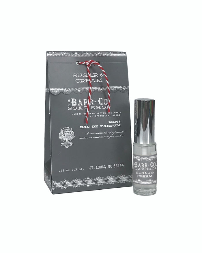 A gray Barr-Co. gift bag labeled "Sugar & Cream" sits beside a clear Barr-Co Sugar & Cream Mini Perfume spray, both adorned with matching labels and red-and-white twine—perfect for gifting, all set against a white background.