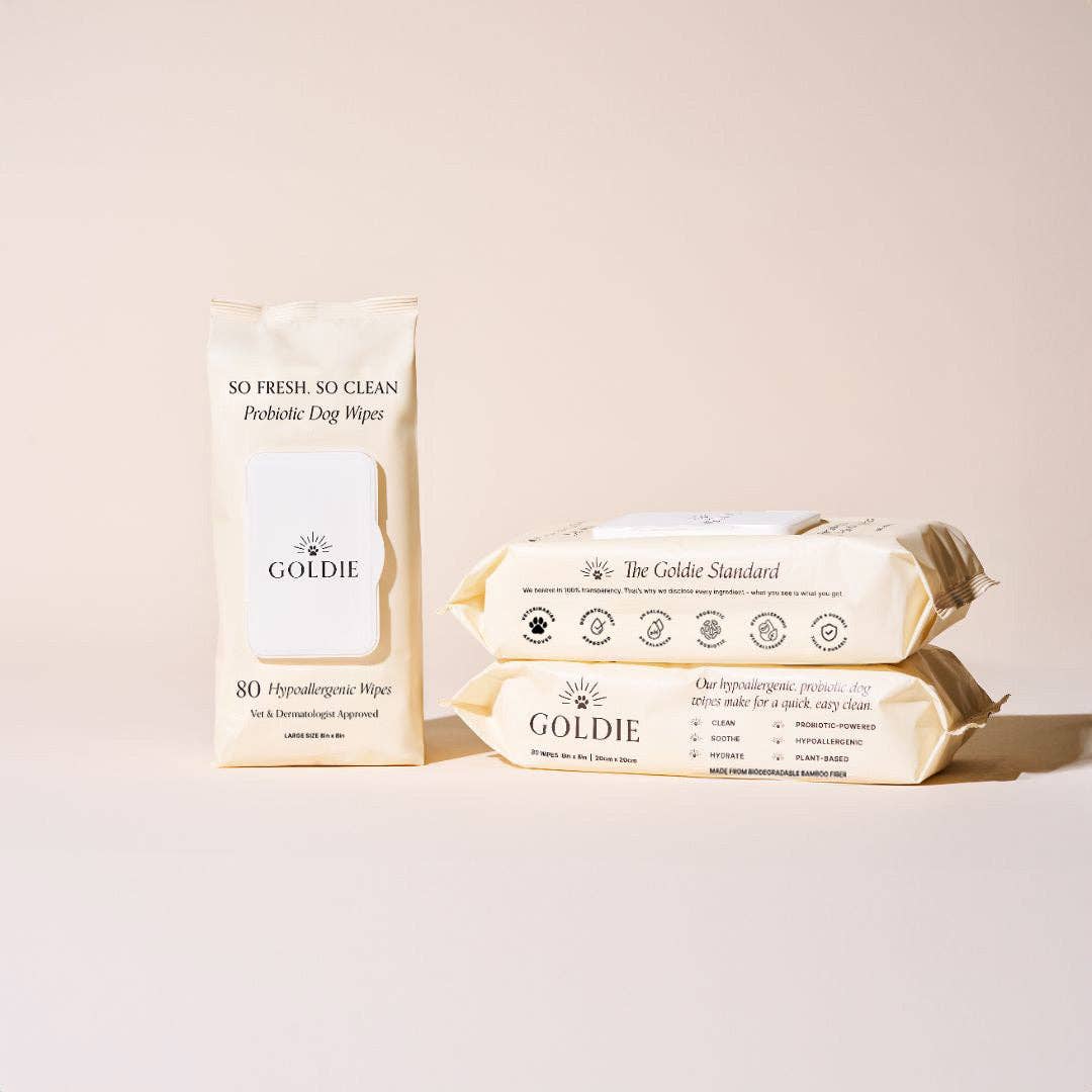 Three beige packs of Goldie - So Fresh, So Clean Probiotic Wipes are displayed on a light beige background, showcasing these gentle, hypoallergenic wipes—ideal for incorporating into your dog's daily grooming routine.