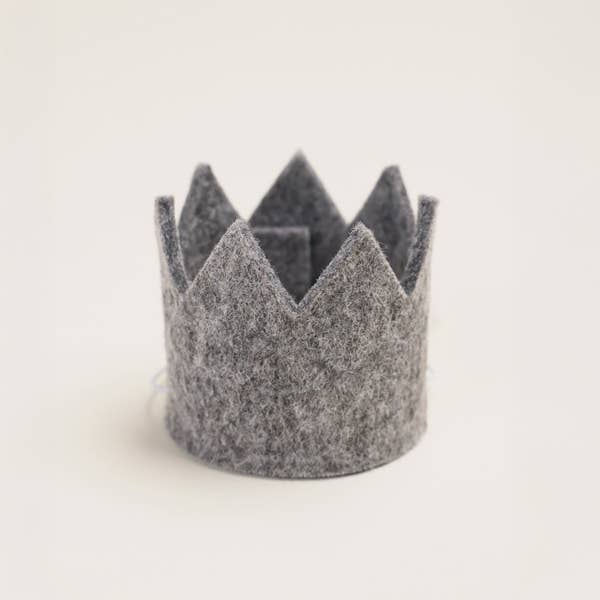 The MODERNBEAST Wool Pet Party Crown, a small gray adjustable crown with pointed tips, sits upright on a light surface—perfect for celebrating your dog's birthday in style.