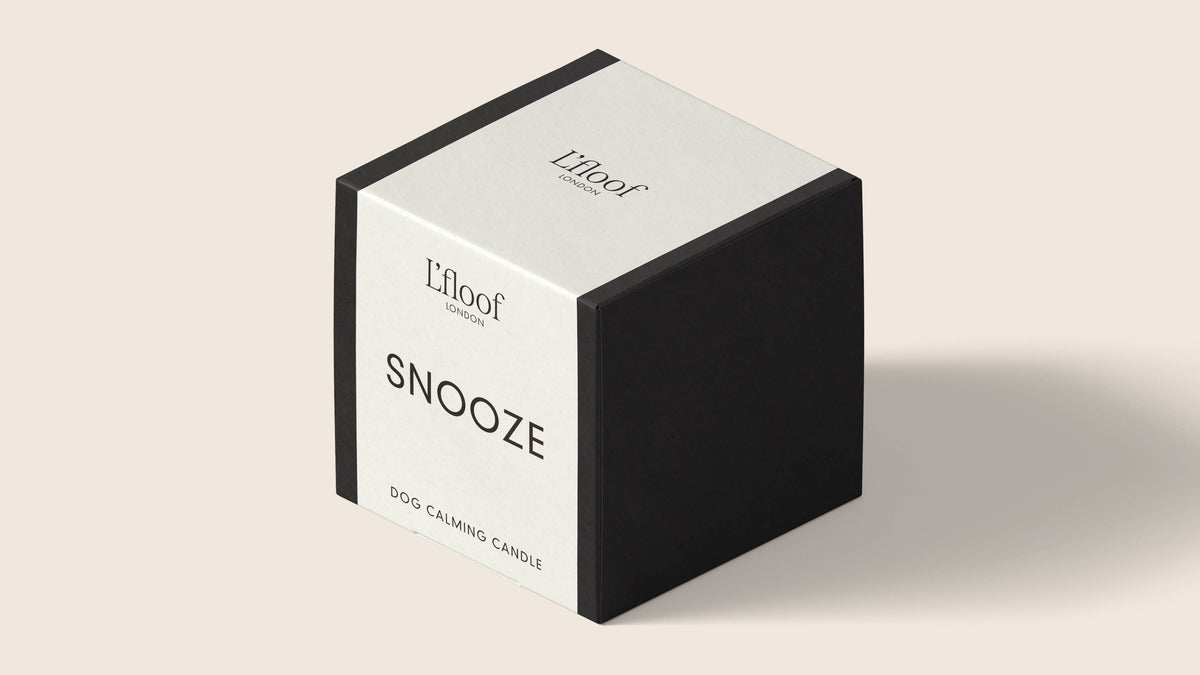 A black and white box labeled "L'floof" and "SNOOZE", with "Dog Calming Candle – Essential Oil – 330ml" at the bottom, designed for relaxation, displayed on a light beige background.