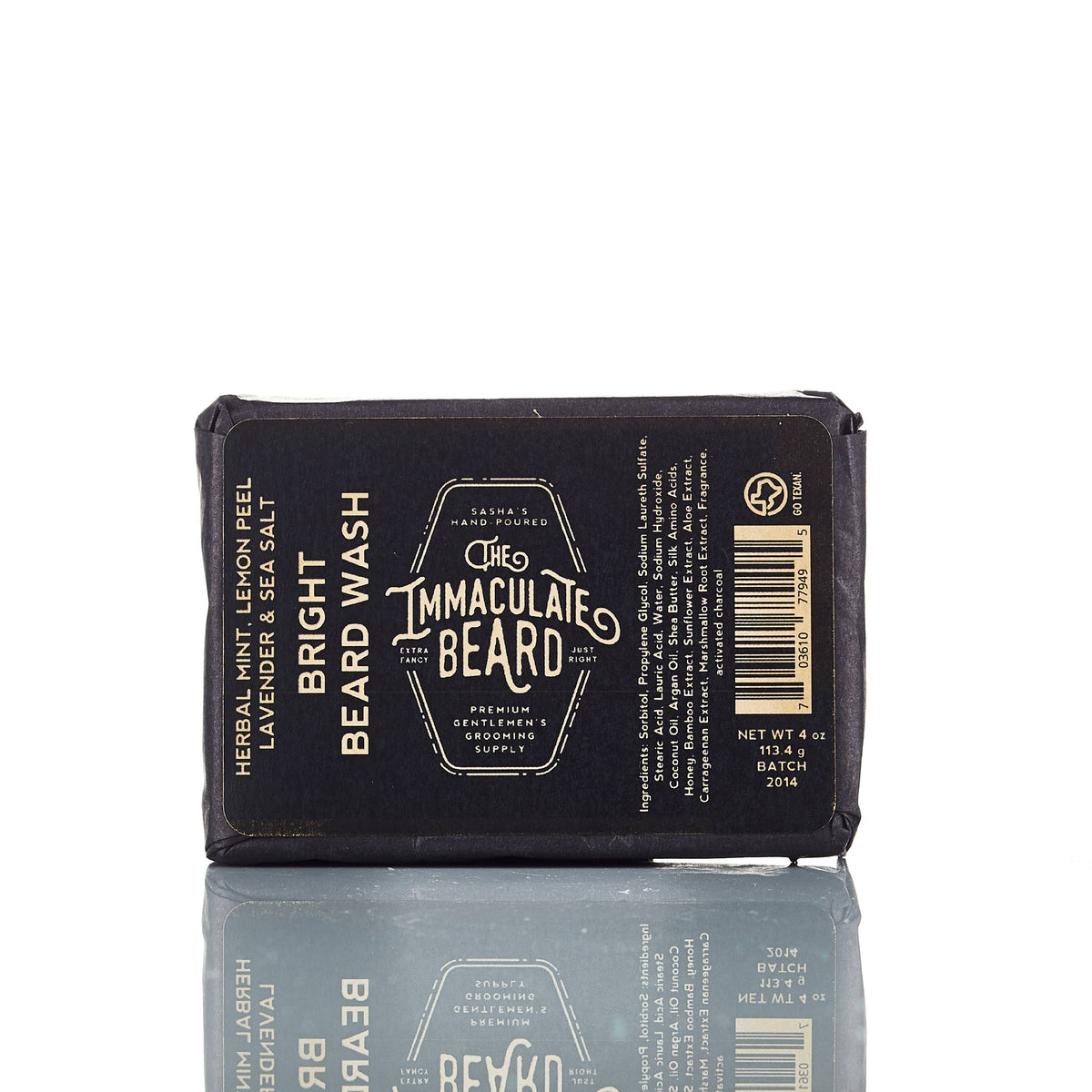 The Immaculate Beard SUNRISE Beard Wash Bar, a black 4 oz charcoal shampoo bar, features herbal mint, lemon peel, lavender, and sea salt for premium beard care. Its packaging is reflected on a white surface.
